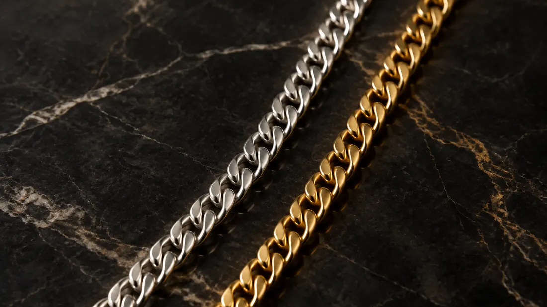 Sterling silver chain and gold chain side by side on dark marble